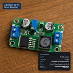 Green PCB adjustable DC-DC boost converter module with blue screw terminals labeled IN+, IN-, OUT+, OUT-, labeled with its at-a-glance specs.