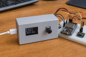 Small enclosure with 0.96 inch OLED display and rotary encoder knob, ESP32-S3 and AHT20 sensor on breadboard