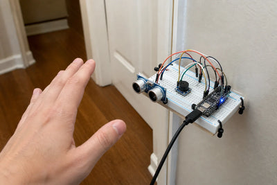 Breadboard with HC-SR04 ultrasonic sensor, buzzer and ESP32-C3 mounted near a doorway