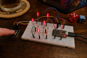 Breadboard with five individual LEDs lit in a dice-face pattern and a push button, ESP32-C3 SuperMini, game night table