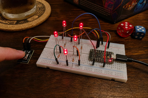Breadboard with five individual LEDs lit in a dice-face pattern and a push button, ESP32-C3 SuperMini, game night table