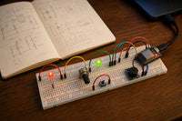 Tidy breadboard with LEDs, potentiometer, push button, buzzer and ESP32-C3, notebook with circuit sketches