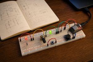 Tidy breadboard with LEDs, potentiometer, push button, buzzer and ESP32-C3, notebook with circuit sketches