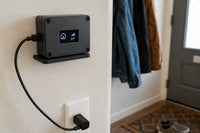 Small plastic project enclosure with a 0.96 inch OLED display showing home status icons, mounted near an entryway