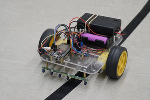 2WD robot car chassis kit with ESP32-S3, TB6612FNG motor driver, and 5-channel IR line sensor array following a black line