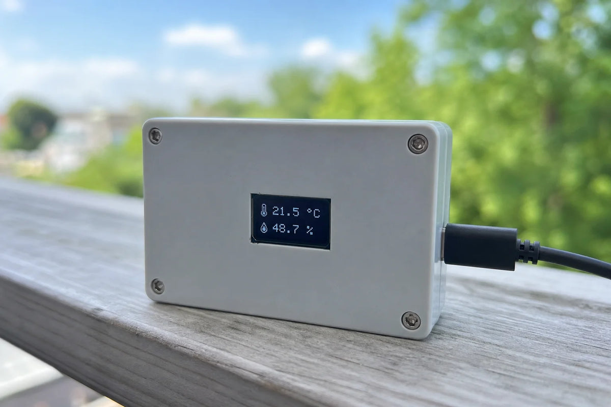 Small enclosure with 0.96 inch OLED showing temperature and humidity, outdoors on a railing