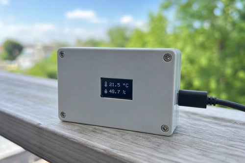 Small enclosure with 0.96 inch OLED showing temperature and humidity, outdoors on a railing