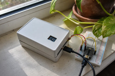 Small plastic project enclosure with AHT20 sensor and ESP32-C3 breadboard, on a windowsill