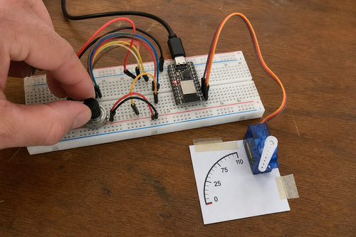 ESP32-C3 SuperMini breadboard build with an SG90 micro servo pointing to a printed scale, controlled by a 10K potentiometer