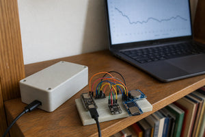 Small enclosure and breadboard with ESP32-C3, AHT20, SD card module and DS3231 RTC, laptop showing logged data graph
